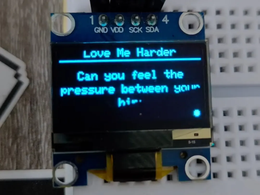 The ESP32 OLED showing a song title and lyric line